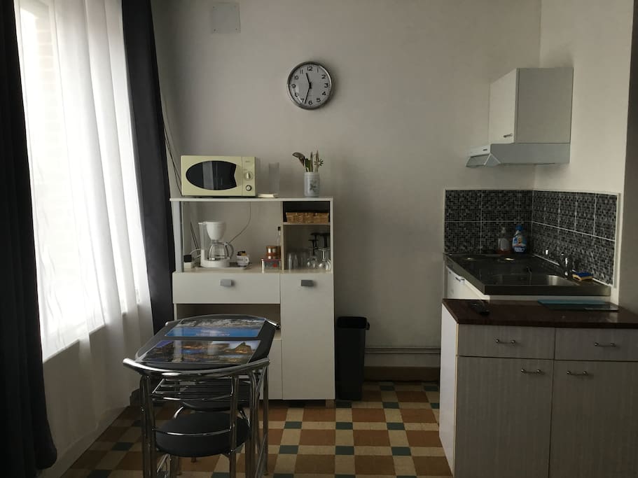 Coin cuisine avec la vaisselle, micro-onde, cafetière (café, sucre), réfrigérateur, plaques de cuisson