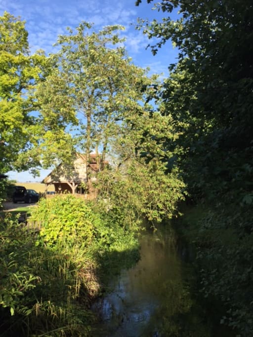 View towards barn annexe from the bridge over the river. The chalk river is dry from September - February.