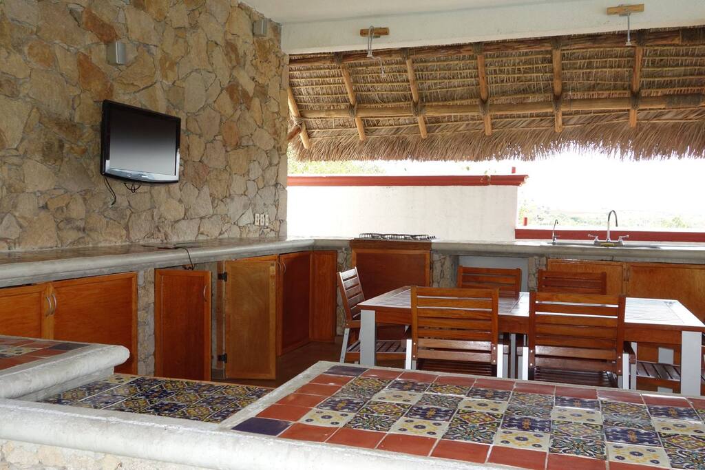 Palapa equipada con refrigerador doble, 1 tarja doble y 1 tarja sencilla, hielera, desayunador, frigobar, parrilla con 4 calentadores de gas, modular y pantalla plana de 32”.