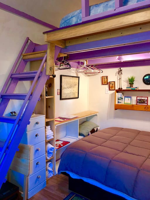King bed above, queen bed below. Small folding table. Towels. Hangers.