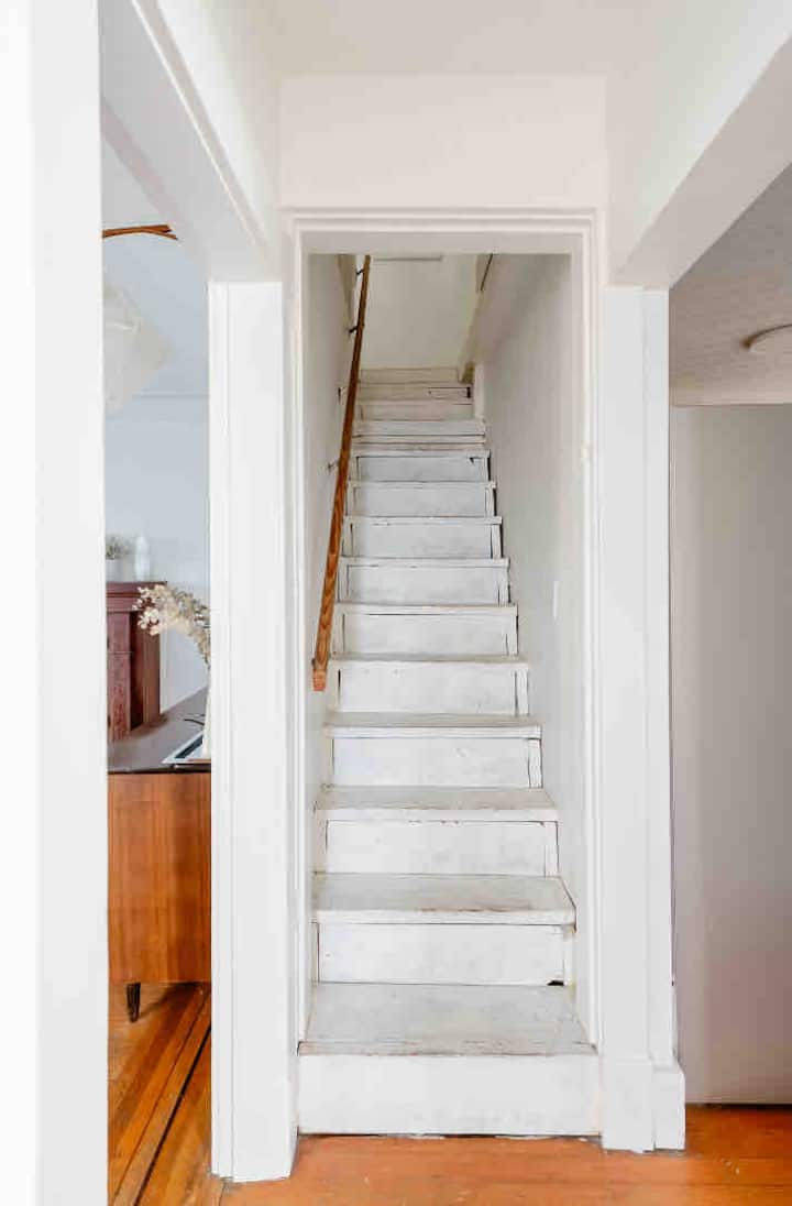 Tangga di seberang kamar mandi yang memisahkan ruang tamu dari dapur. Suite utama 400 sf di lantai atas. Tempat tidur king dan setengah kamar mandi tersedia HANYA ATAS PERMINTAAN dengan biaya tambahan. 