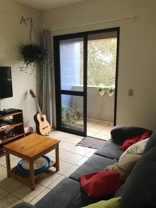 Sala aconchegante com sacada e vista para o bosque.