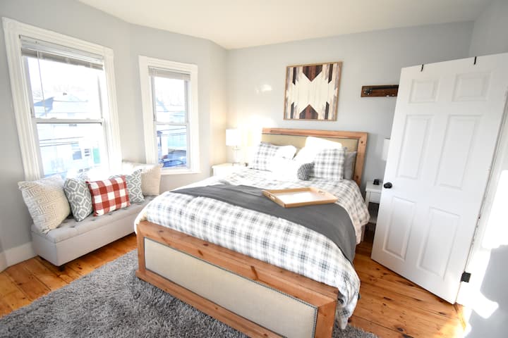 El dormitorio delantero cuenta con una cama tamaño queen y cuatro ventanas, inundando la habitación con luz por la tarde.  ¡Un gran espacio para retirarse y relajarse!  Cada mesita de noche incluye cargadores para tu teléfono (dos puertos USB, además de un enchufe) y un portaequipajes.