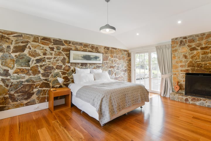 Plush king sized bed with view over farm through large glass sliding door that opens onto the deck. A great place to curl up on a winter's night with the open fire glowing.