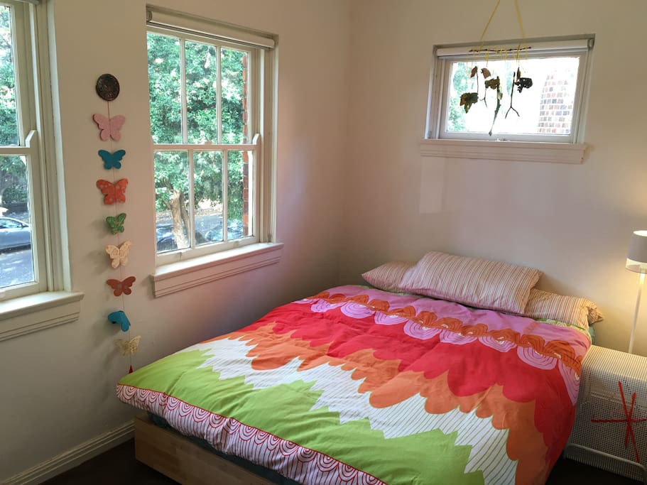 Bright room with a queen size bed and access to a small wardrobe.