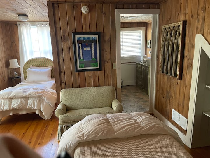 Dormitorio con 2 camas individuales idénticas (ambas con colchones nuevos), se conecta al baño compartido y al gran porche con mosquitero.