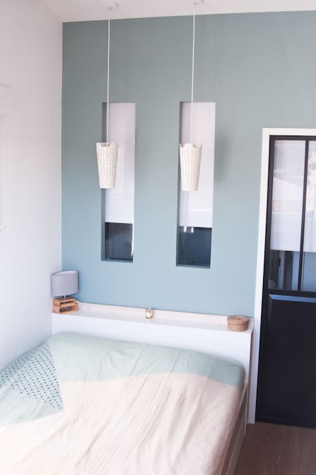 Chambre avec double dressing et 2 fenêtres. En arrière plan on aperçoit la SDB.