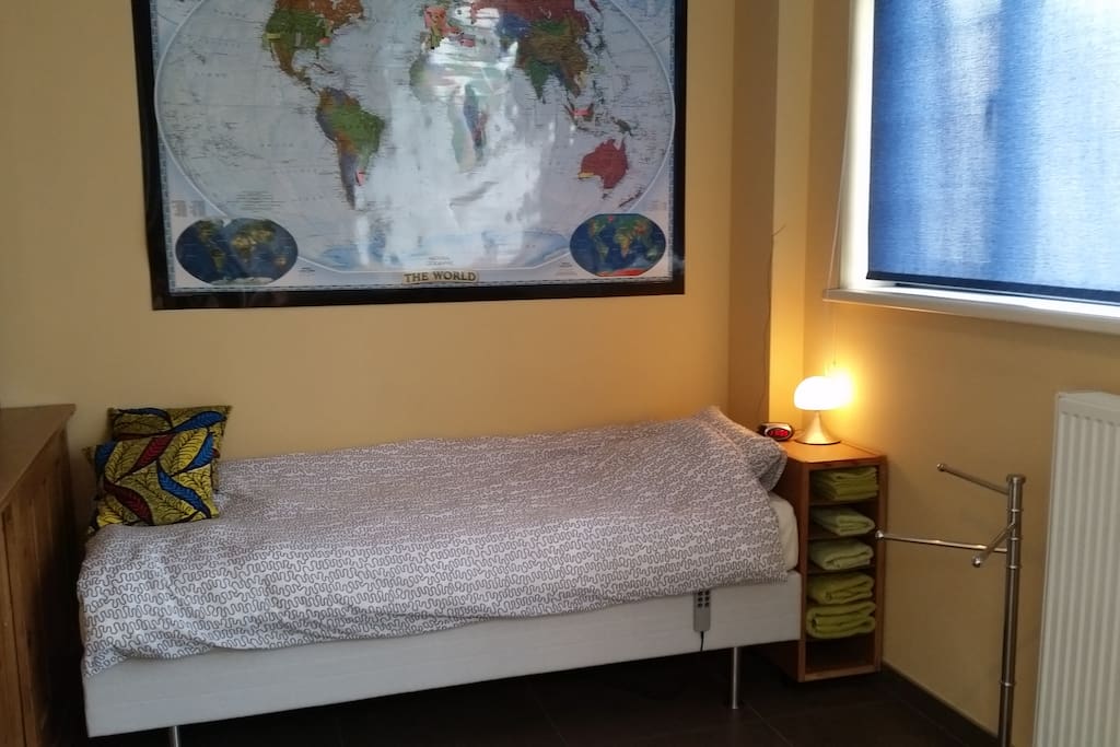 Your room: Bed with clock radio, light and roller blind.