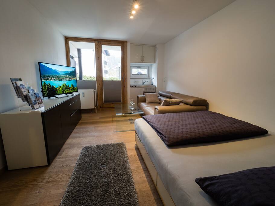Wohnraum mit Mini-Einbauküche und Zugang Balkon