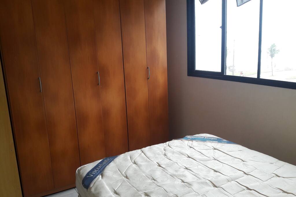 Quarto com cama de casal e guarda roupas.