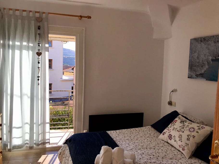 Habitación de matrimonio donde entra mucha luz por la ventana exterior donde hay un balcón.