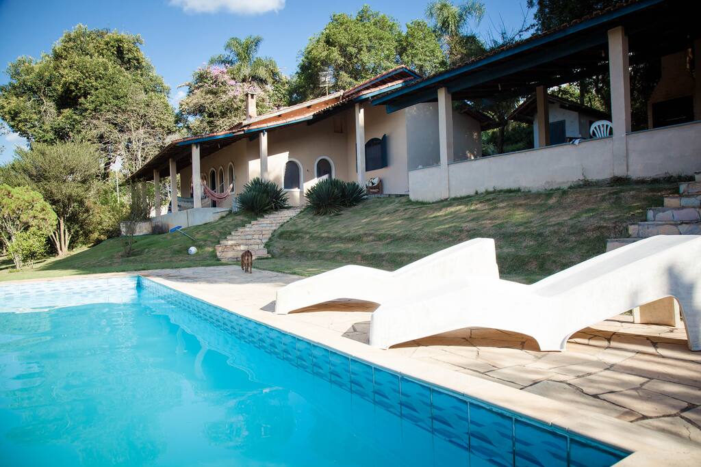 Piscina com churrasqueira e casa ao fundo.