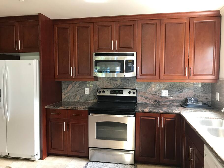 Fully stocked large kitchen which includes eight barstools and a table with four chairs
