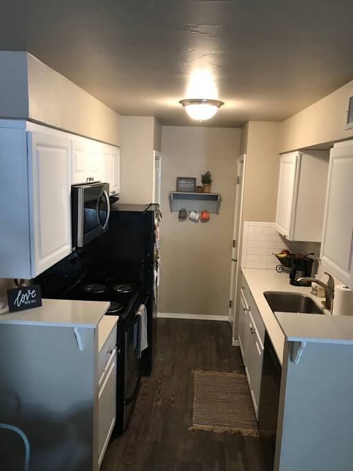 Kitchen includes a coffee pot, microwave oven, and a stove top.