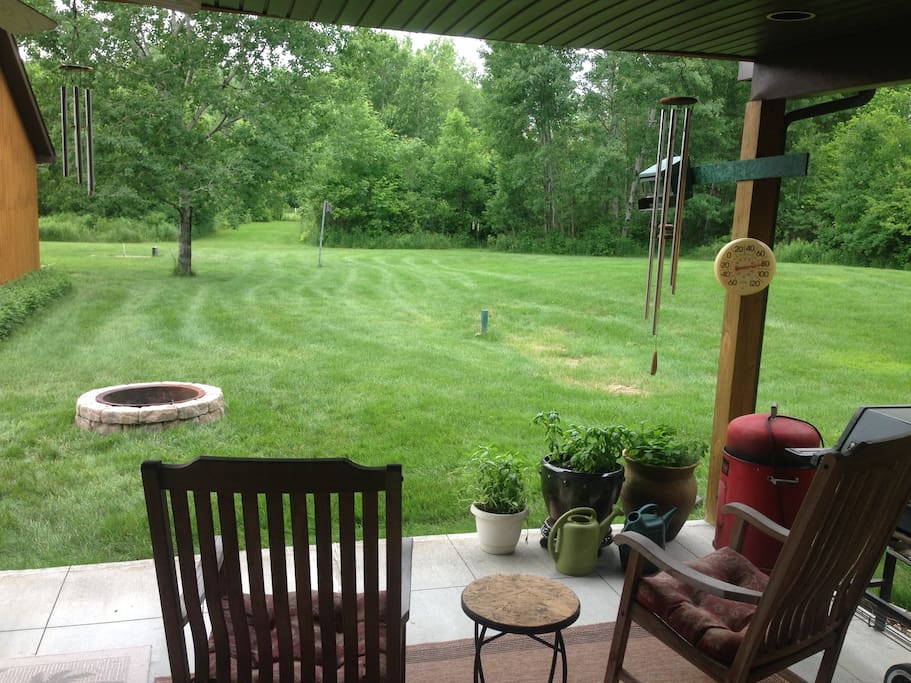 Large patio with gas grills, rockers, table and chairs, and large yard with fire pit (wood provided), horseshoe pit, and wooded trails.