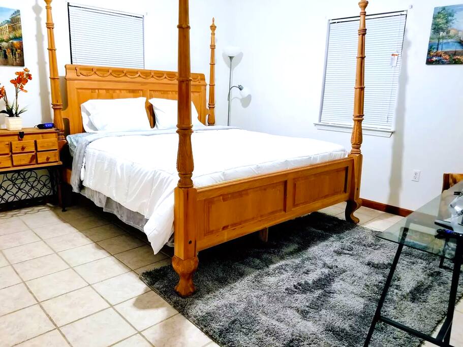 Bedroom with 4-poster bed, lamp, nightstand, armoire, and TV.