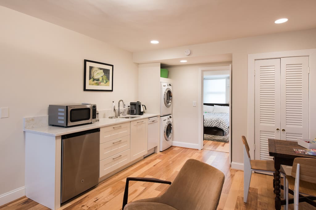 Wet bar/kitchenette with sink, dishwasher, new mini fridge, microwave, new electric kettle, new Nespresso espresso/coffee machine (not pictured), new washer/dryer; with bedroom in background