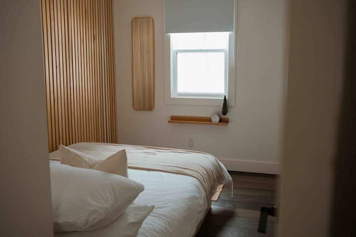 Peaceful, minimalist bedroom with cozy textures and forest-facing window.
