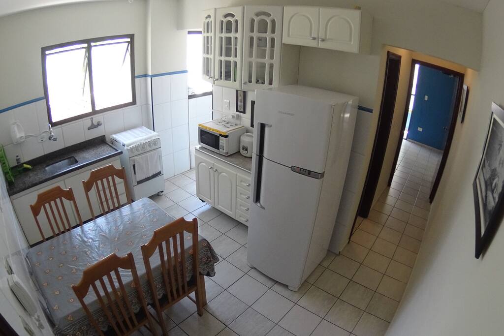 Cozinha completa, geladeira, fogão, microondas, panela de arroz, liquidificador, panelas, pratos, copos, talheres, mesa jantar, filtro de água.