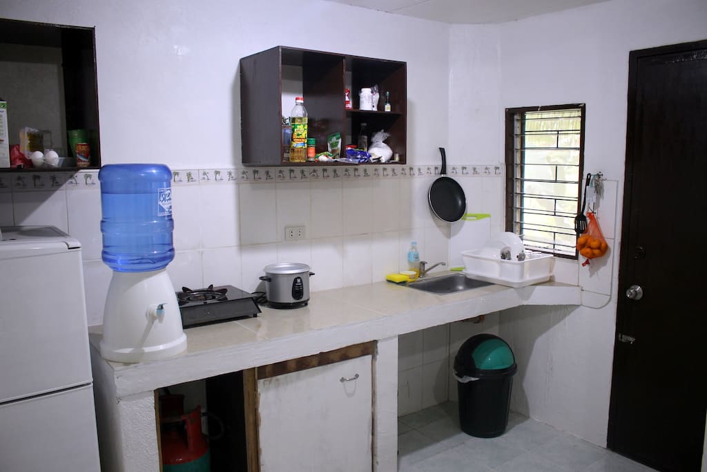 The kitchen - fridge, gas stove, rice cooker, kettle, plates and cutlery.