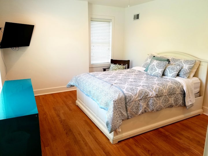 Двойно легло на горния етаж със самостоятелна баня. Гардероб за окачване на предмети,  рафтове,  телевизор и изглед към тревата на дюните отзад.  