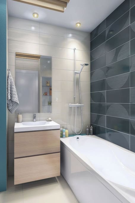 Salle de bain avec baignoire et vasque sur meuble bois suspendu. WC attenant séparé par porte