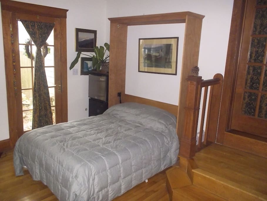 Bed drops down from a cabinet on the wall, with a small frig in the corner