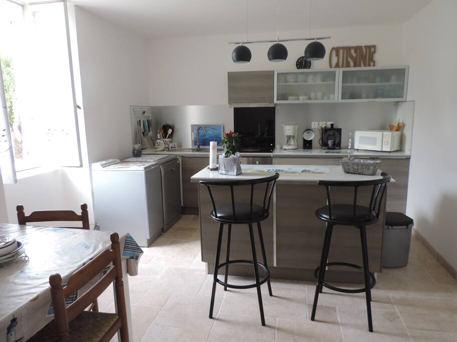 îlot central avec tabourets de bar mais aussi table pour déjeuner.