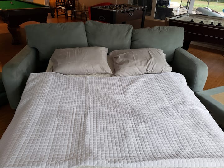 Sofá dobrável que está na sala de jogos, que normalmente é usado pelas crianças que querem ficar acordadas brincando a noite toda.