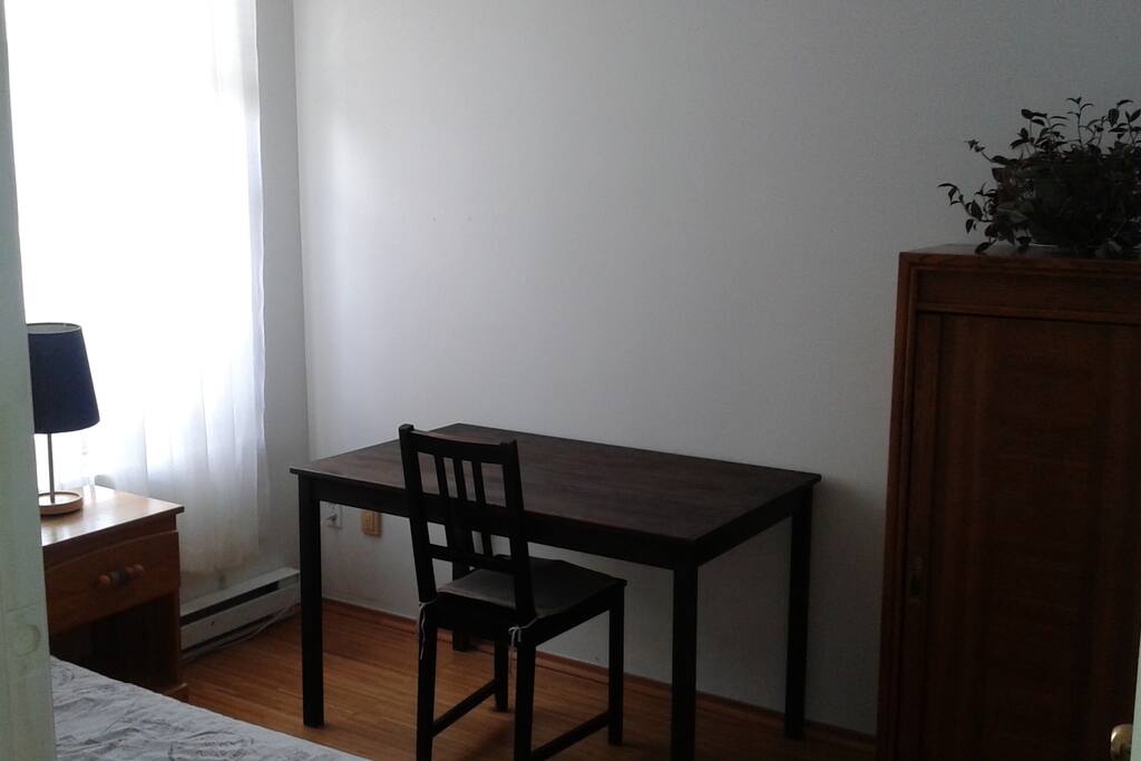 Room has a table, chair, lamp, nightstand and cupboard.