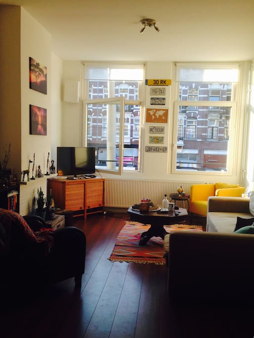 The spacious living space with large double-glazed windows - the evening sun shines in and you overlook the street full of restaurants, shops and bars