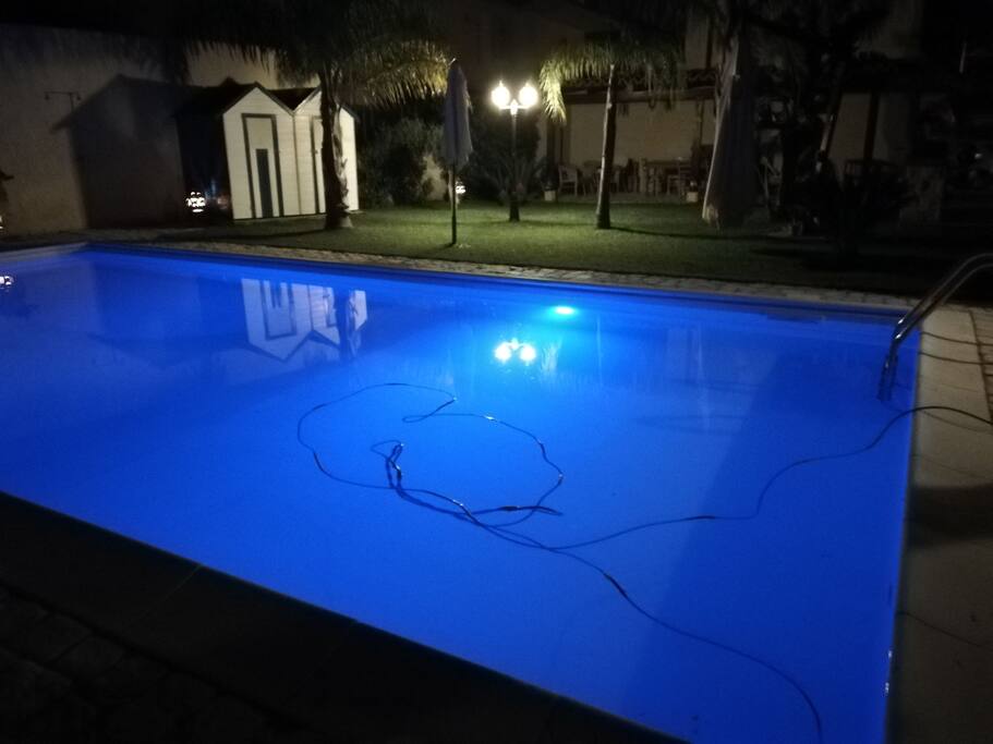 Veduta notturna giardino e piscina illuminata con luci a led colorate.