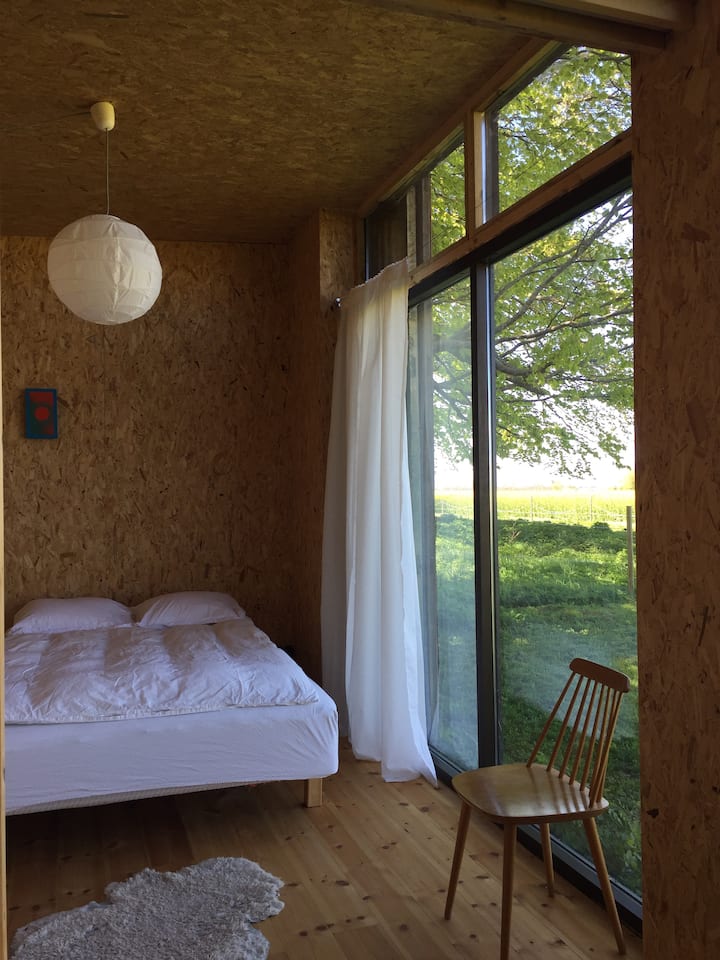 ห้องนอนใหญ่มีหน้าต่างจากพื้นจรดหลังคาไปยังทุ่งนา