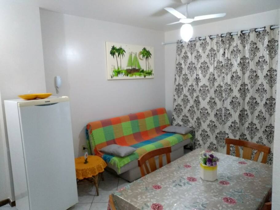 Sala com sofá-cama, mesa de jantar e ventilador de teto.