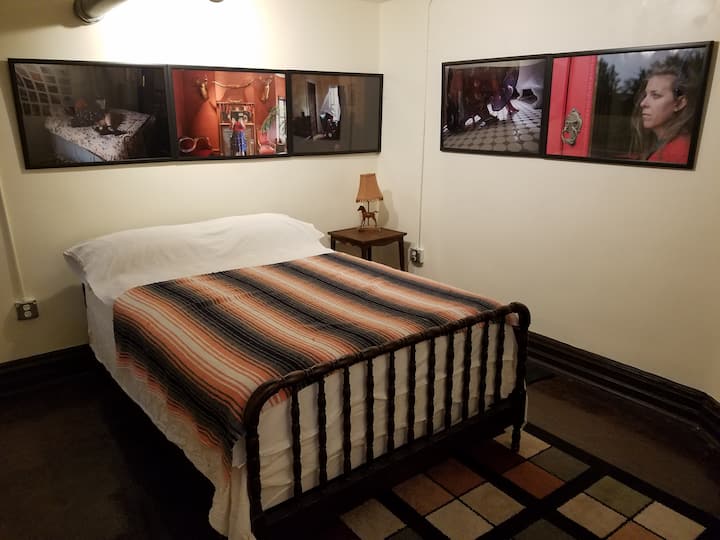 フルサイズのベッドとベンチを備えた小さなベッドルームで、スーツケースを休めることができます。