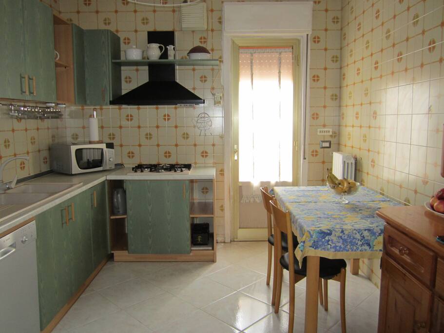 Cucina con cappa, forno a microonde, fornelli a gas, tavolo e sedie
