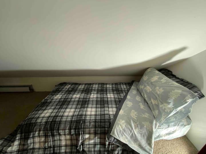 Een loft met twee tweepersoonsbedden die in de dakrand zijn ingebouwd.