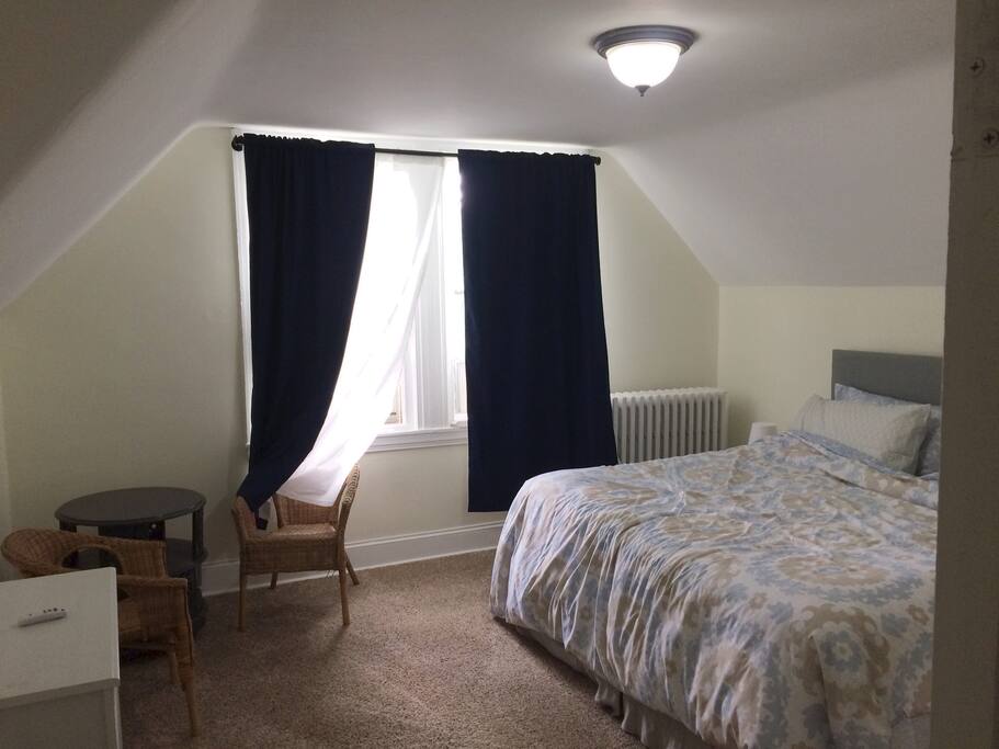 The main bedroom receives plenty of sunlight and is equipped with a King-Size bed, air conditioning unit, dresser, table with chairs and plenty of closet space.