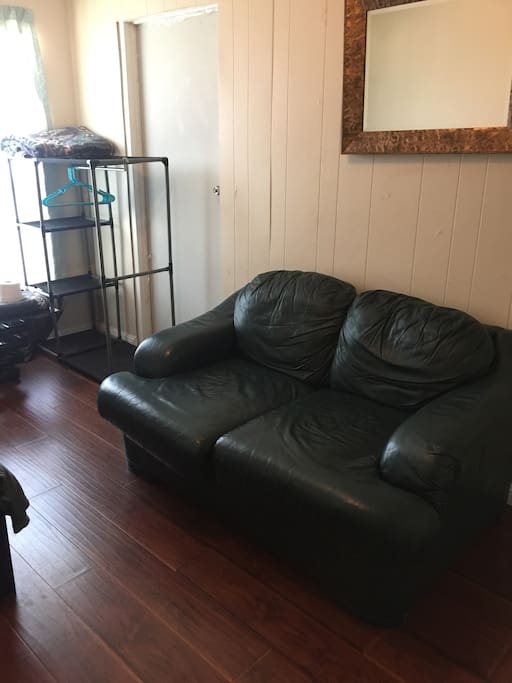 Small couch in room with portable clothing rack