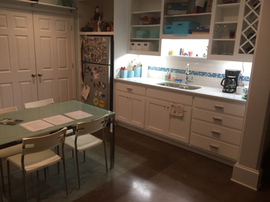 Kitchen area features a full-size fridge, coffee maker, and work/eat table.