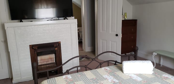 غرفة نوم في الطابق العلوي بسرير وتلفزيون بحجم كبير.