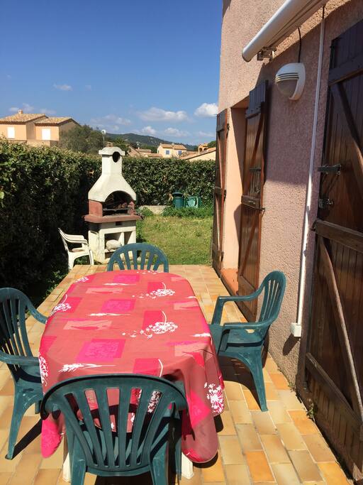 terasse derrière la maison avec le barbecue et un store pour protéger du soleil