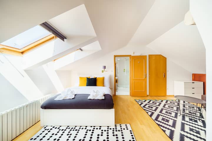 Gezellige slaapkamer in zolderstijl met natuurlijk licht, een comfortabel bed en een ontspannen sfeer.