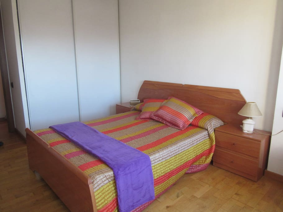 Habitación de matrimonio con dos grandes ventanas al exterior. Radiador en la habitación.