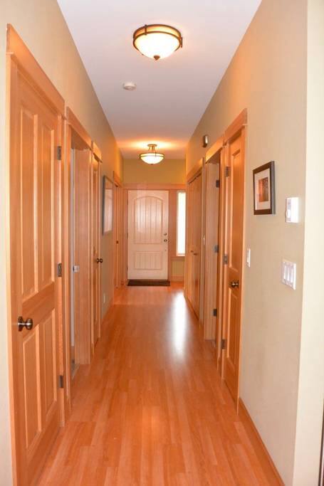 Entry hallway from main living area with doorways leading downstairs, main floor bathroom, queen bedroom, coat closet and main floor laundry room.