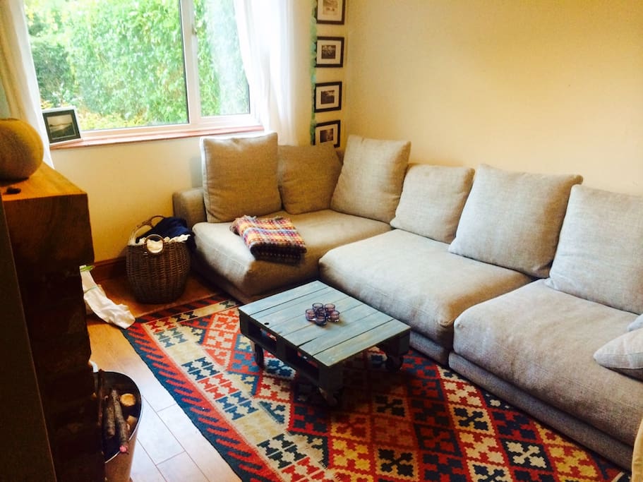 Snug living room with huge sofa & wood burner