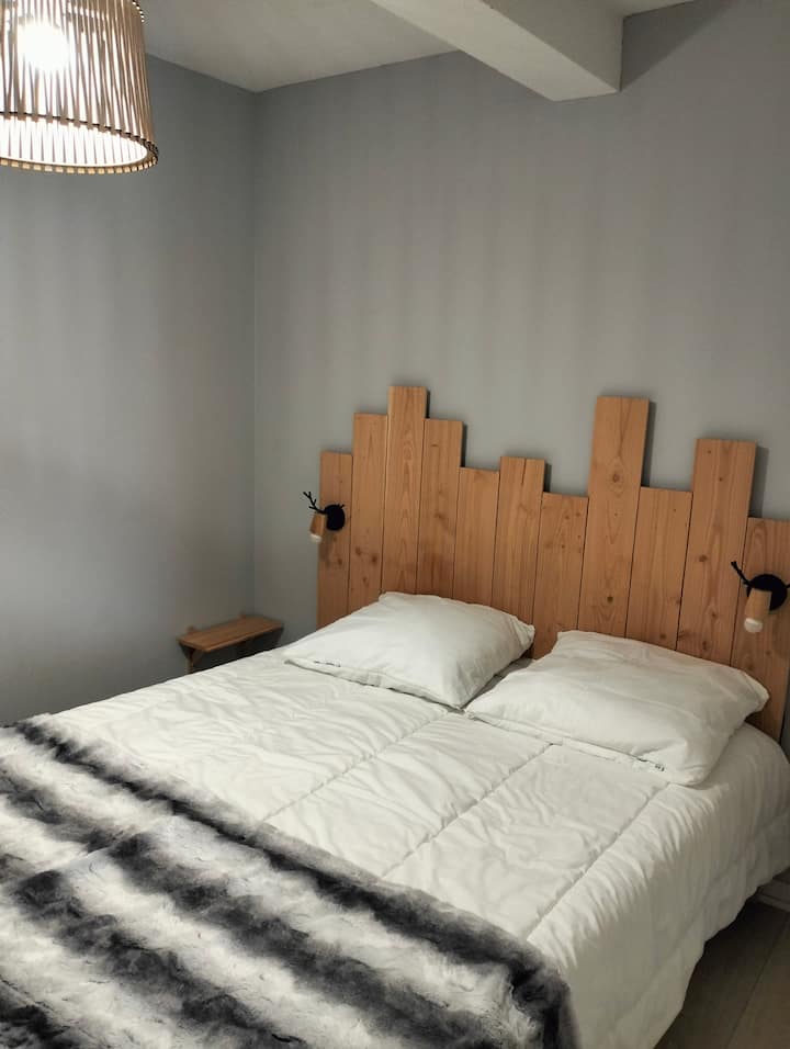 ห้องนอนเตียงคู่ขนาด 140 ซม. พร้อมตู้เสื้อผ้าและทีวีที่แขวนอยู่ประตูหน้าต่าง