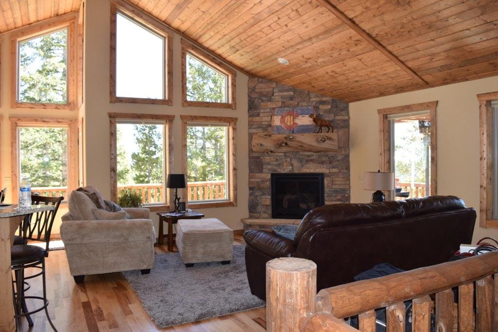 The spacious great room has comfy seating, a gas fireplace and high vaulted ceilings with floor-to-ceiling windows.