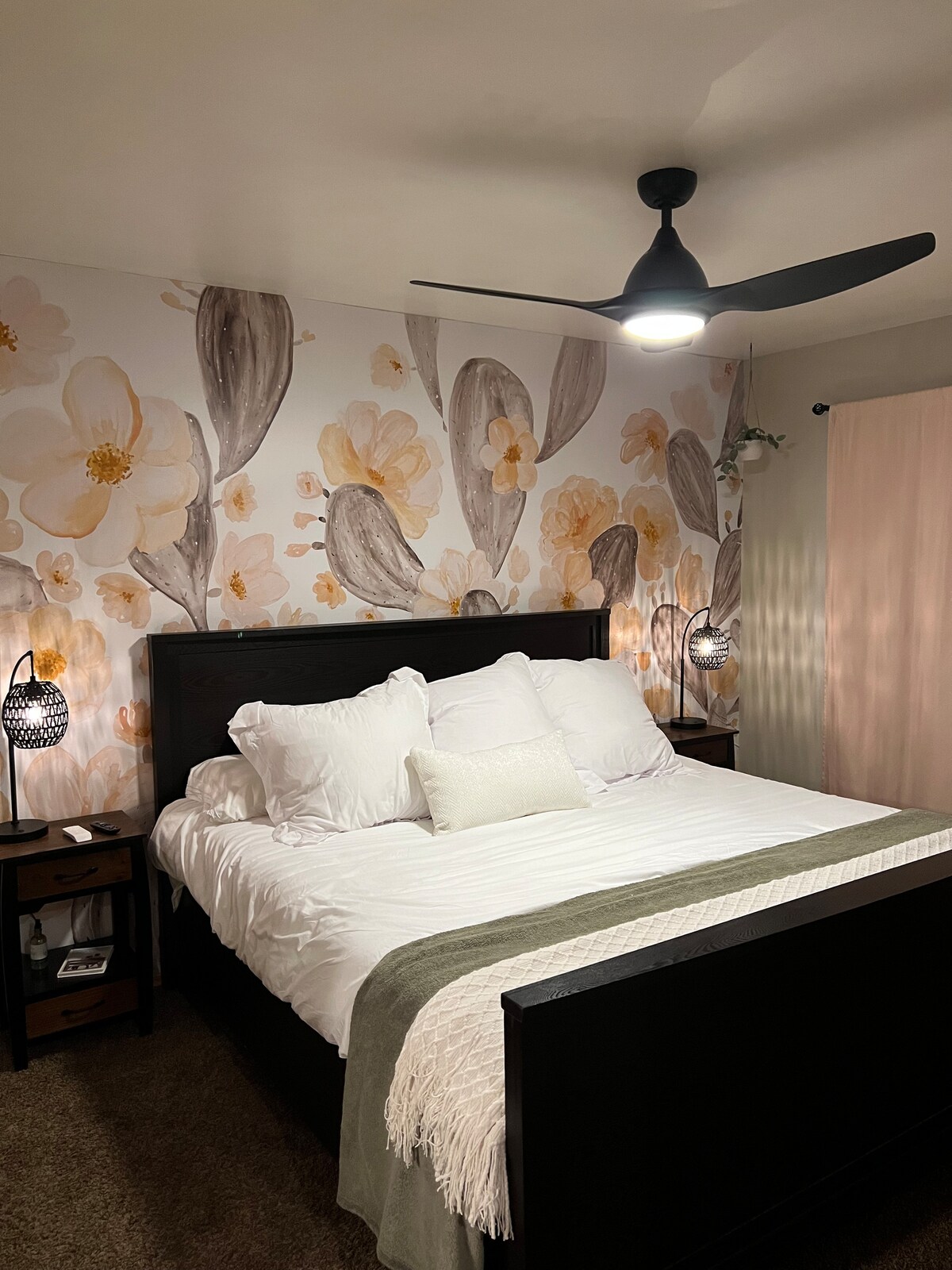 Dormitorio principal con cama tamaño king, lámparas, ventilador de techo y televisor de pantalla plana de 43 pulgadas colgado en la pared. 