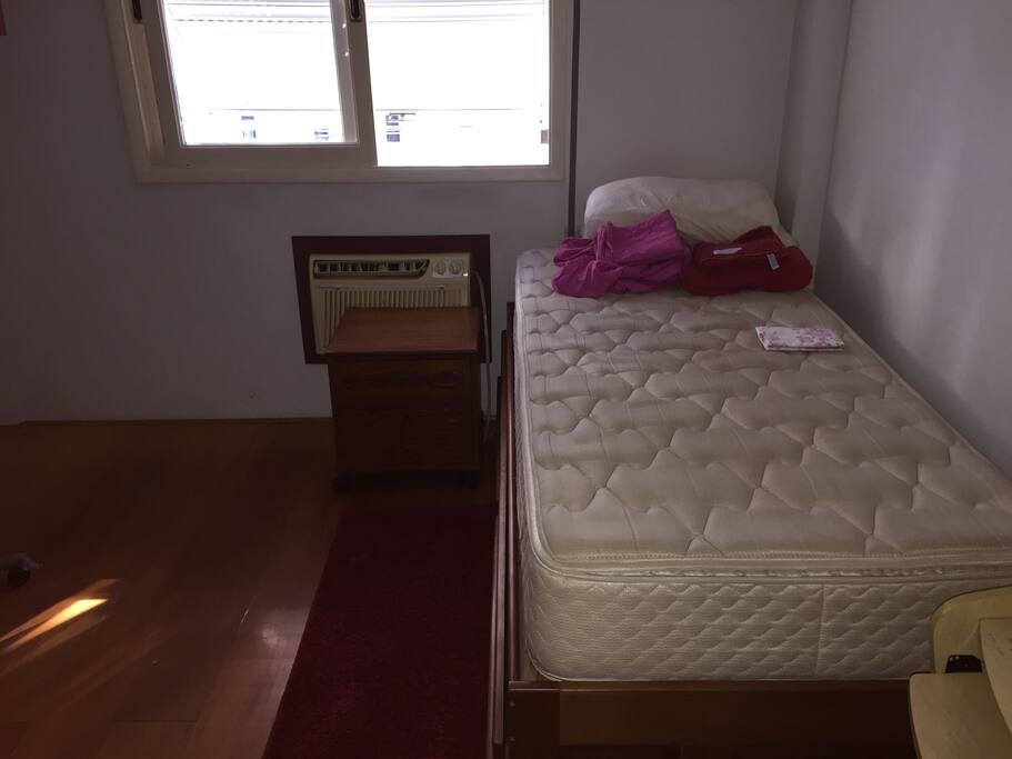 Quarto de solteiro com cama e colchão no chão. O quarto maior possui cama de casal queen